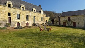 Ein Gebäude aus Stein mit Innenhof, Außenbestuhlung und blauem Himmel.
