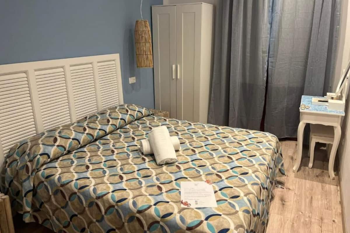 A hotel room with a bed, a wardrobe, a desk, and a curtain.