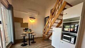 Eine kompakte Küche mit einer Holztreppe, einem Essbereich mit Hockern und einer eingebauten Mikrowelle.