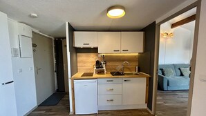 Eine kleine Küche mit Spüle, Kaffeemaschine und Geschirrspüler.