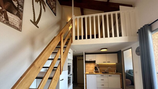 Eine moderne Küche mit weißen Schränken, einer Holztreppe und einem Essbereich mit Holztisch und -stühlen.