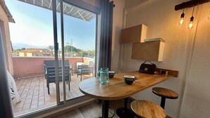 Ein moderner Essbereich mit einem Holztisch, zwei Hocker, einer Karaffe und einer Kaffeetasse.