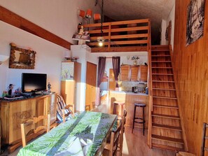 Un ambiente accogliente con zona pranzo, televisione, mobili in legno e cucina.