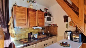 A compact kitchen with wooden cabinets, a microwave, a washing machine, and a toaster. - Central apartment, pets allowed - 6 guests (Saint-Michel-de-Chaillol)