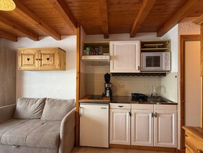 A compact kitchen with white cabinets, a microwave, and a coffee maker. - Apartment mountain view - 4 guests (Crest-Voland)