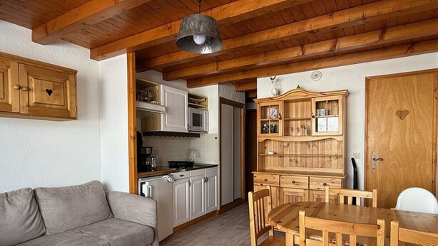 Eine gemütliche Küche mit Holzschnitzereien, einem Esstisch und einer Couch.
