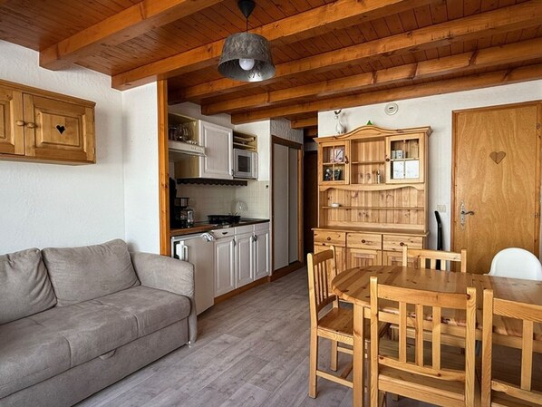A cozy kitchen with wooden cabinets, a dining table, and a sofa. - Apartment mountain view - 4 guests (Crest-Voland)
