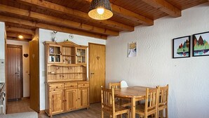 Ein Holztisch mit vier Stühlen, eine Holzkabine mit Glastüren und eine hängende Leuchte.