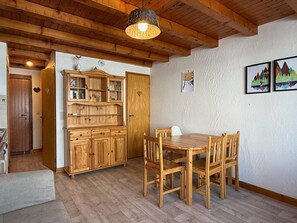 A wooden dining table with four chairs, a wooden cabinet with glass doors, and a hanging light fixture. - Apartment mountain view - 4 guests (Crest-Voland)