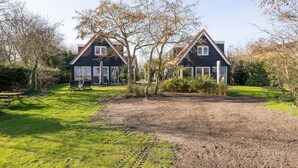 A two-story house with a sloped roof, a front porch, and a well-maintained lawn. - Luxury, Peace and Space for the Whole Family (De Koog)