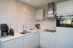 A modern kitchen with a built-in coffee maker, a sink, and a stove. - Luxury, Peace and Space for the Whole Family (De Koog)