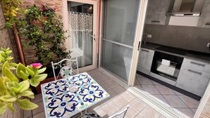 Eine Terrasse mit Tisch und Stühlen, eine Glastür zum Verschieben und ein Küchenbereich mit modernen Geräten.