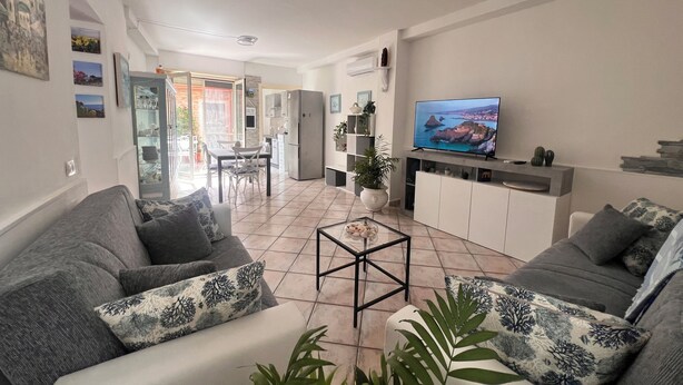 Ein Wohnzimmer mit Fernseher, Sofas, Couchtisch und einem Essbereich mit Stühlen und einem Tisch.