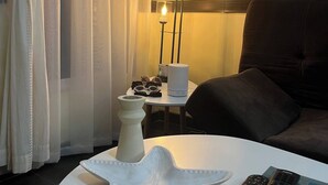 A room with a white table, a white vase, a pair of sunglasses, a remote control, and a candle holder with candles. - The Perfect Nest a Block Away to the Beach (Jacó)