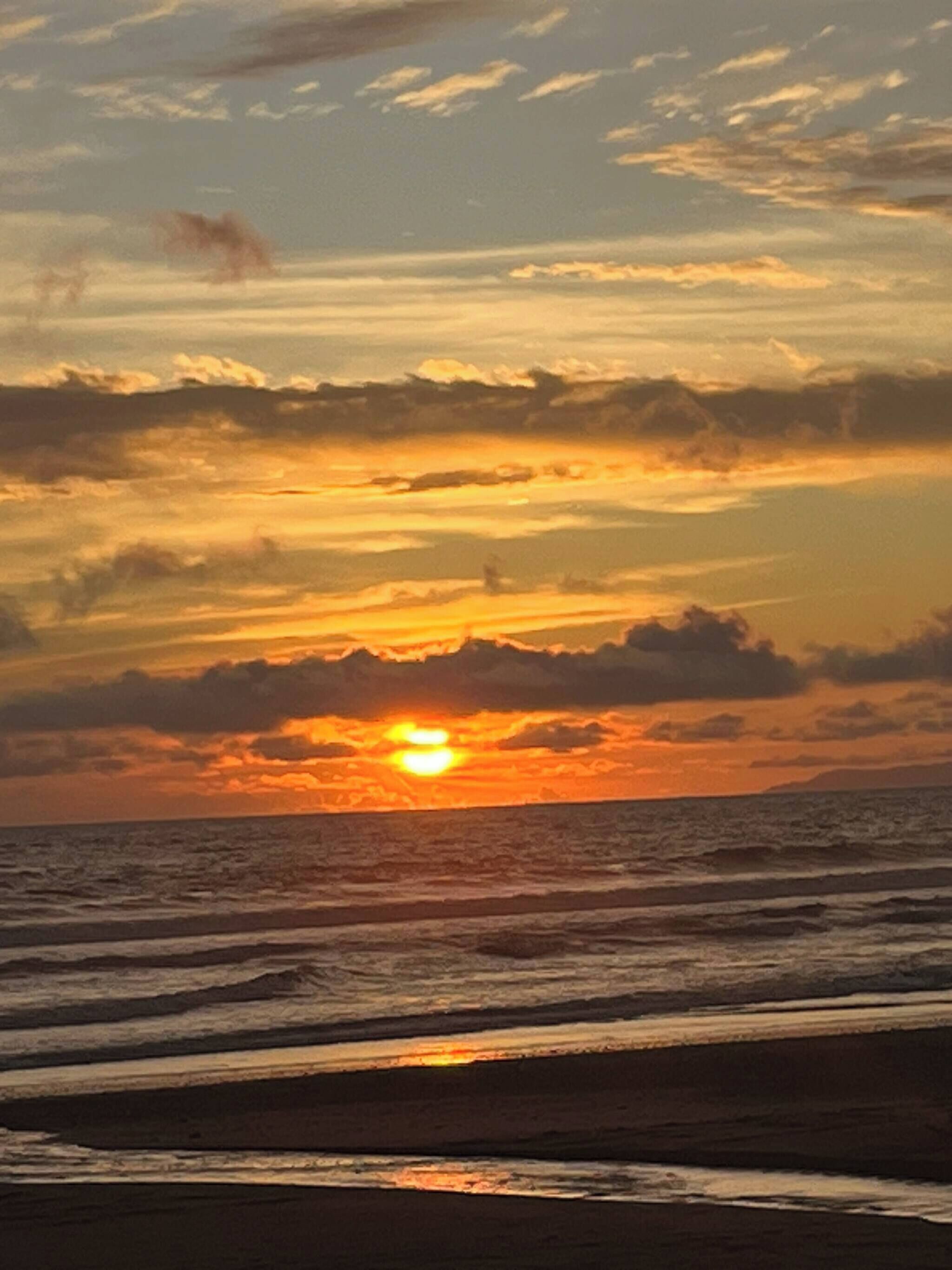 A sunset over the ocean with clouds in the sky.
