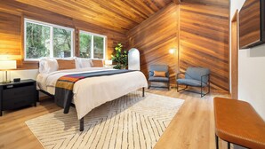 Una camera da letto moderna con soffitto in legno, un letto grande, comodini, una poltrona e una TV a parete.