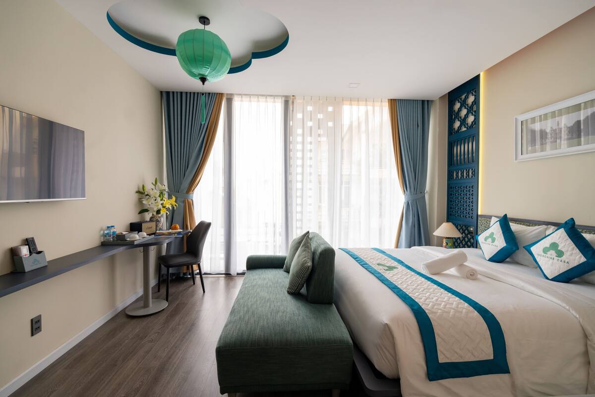 Une chambre d’hôtel équipée d’un lit, d’un bureau, d’une chaise, d’une télévision et d’une fenêtre avec des rideaux.