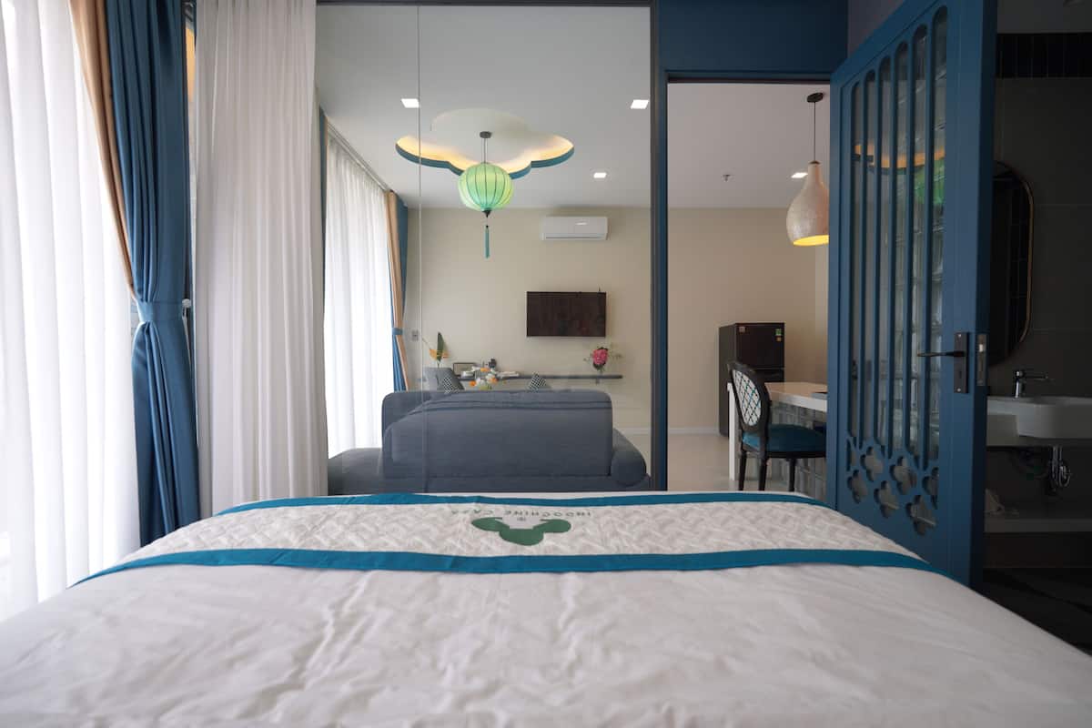 Une chambre d’hôtel comprenant un lit, un bureau, une chaise, une lampe de bureau, un téléviseur fixé au mur et une salle de bain avec un lavabo et un miroir.