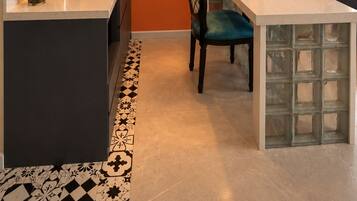 Una cocina moderna con una isla central, una zona de comedor con una silla y un cuadro en la pared.
