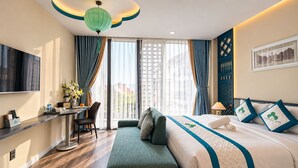 Une chambre d’hôtel avec un lit, un bureau, une banquette et un téléviseur.