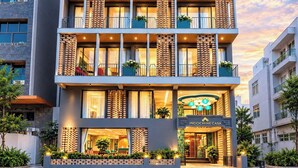 Un hôtel à plusieurs étages, doté de balcons, d’une entrée bien visible et d’une enseigne indiquant « INDOCHINE CASA ».