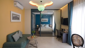A hotel room with a sofa, a desk, a chair, a bed, a television, and a decorative ceiling light. - Indochine Casa Hotel  (Ho Chi Minh City)