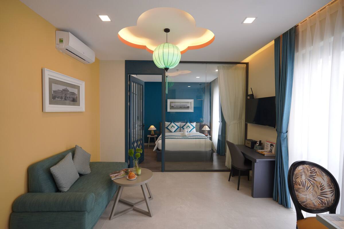 Une chambre d’hôtel équipée d’un canapé, d’un bureau, d’une chaise, d’un lit, d’une télévision et d’un luminaire décoratif au plafond.