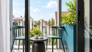 Un balcon avec une table et des chaises, un pot de fleurs et une vue sur les immeubles.