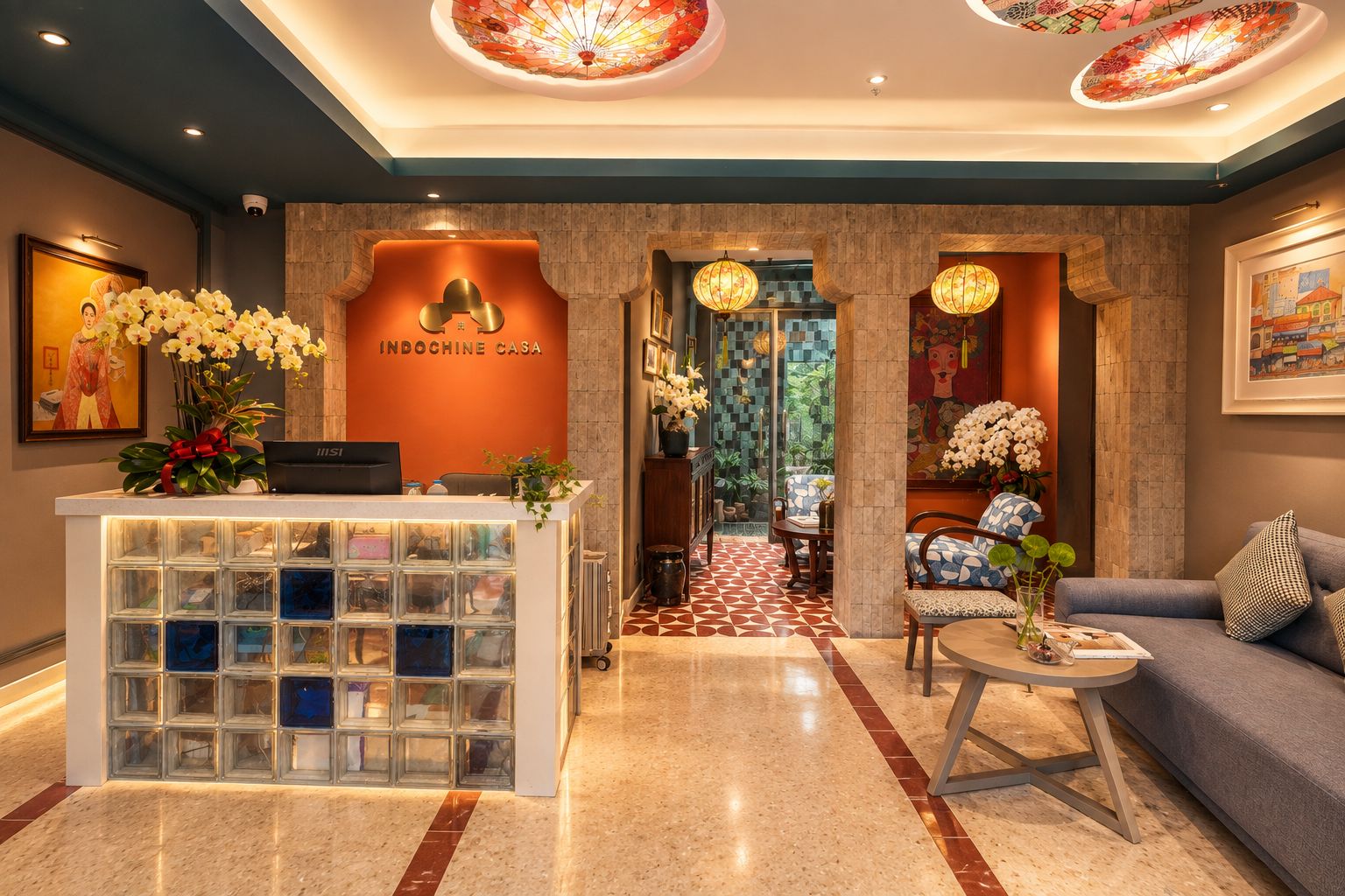 Un área de recepción con mostrador, una sala de estar con sofá y sillones, y un techo decorativo.