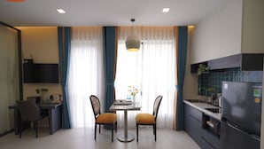 A modern kitchen with a dining table, chairs, and a refrigerator. - Indochine Casa Hotel  (Ho Chi Minh City)