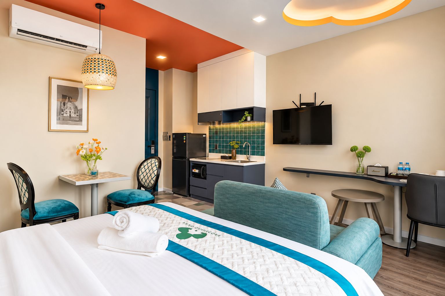 Habitación de hotel con cama, escritorio, kitchenette y televisión.