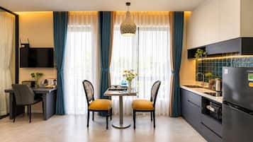 A modern kitchen with a dining area, a flat-screen TV, and a refrigerator.
