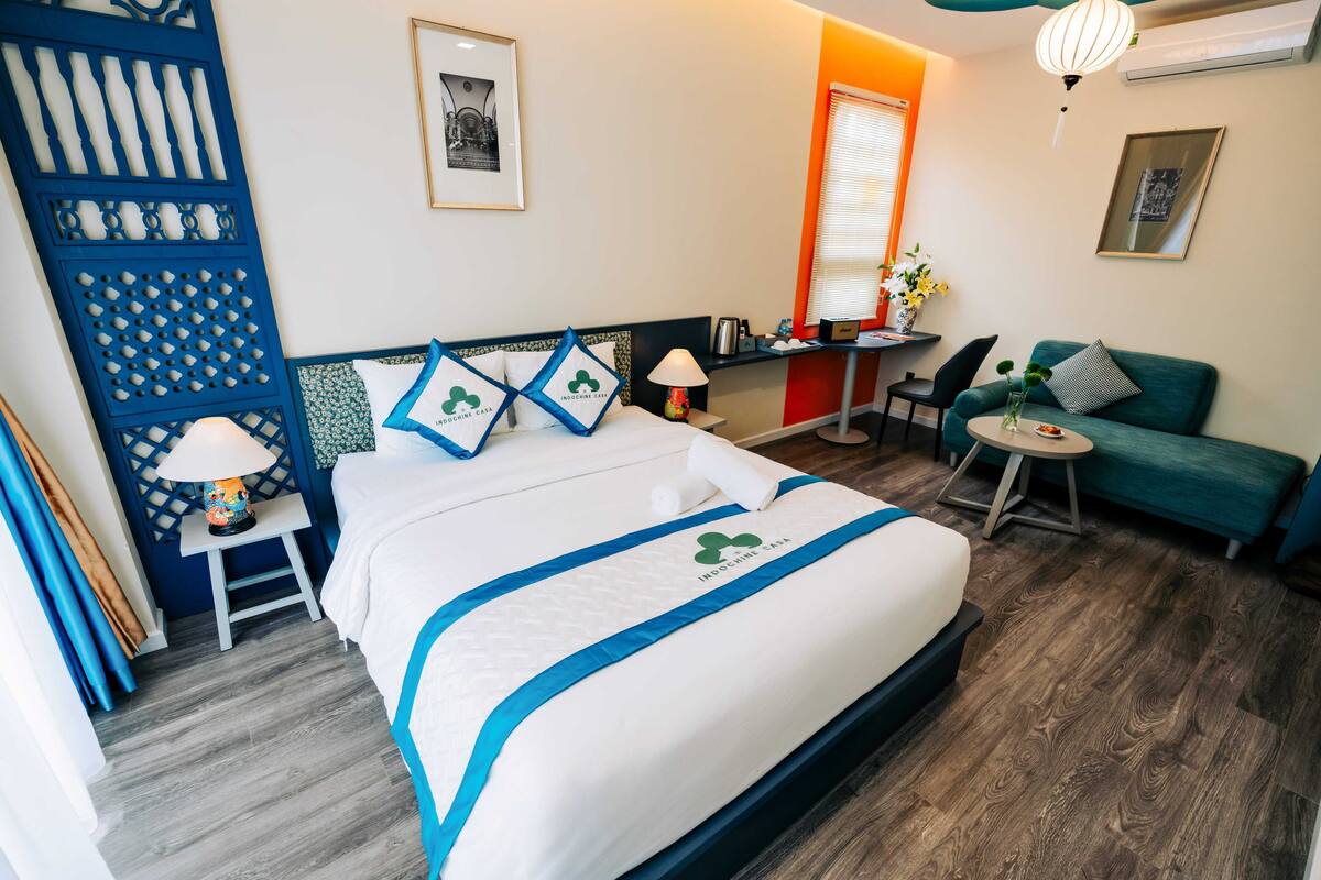 Une chambre d’hôtel avec un lit, une petite table avec une lampe, un canapé et un bureau avec une chaise.