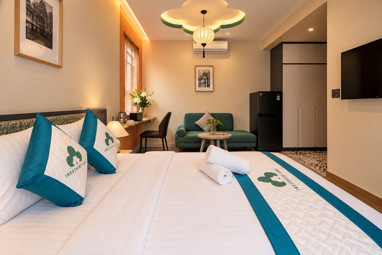 A hotel room with a bed, a desk, a chair, a sofa, a television, and a refrigerator.