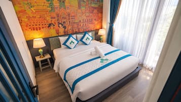 A hotel room with a large bed, a nightstand, a lamp, and a colorful mural on the wall.