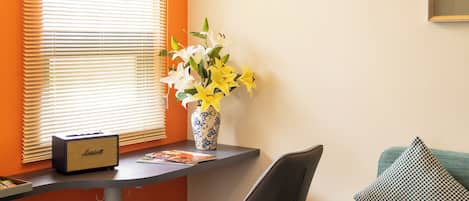 Una habitación con escritorio, silla y sofá con cojín.