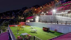 A rooftop terrace with outdoor seating, a swing set, and a view of a hillside. - Townhouse Mall Road Near Library Chowk (Dehradun)