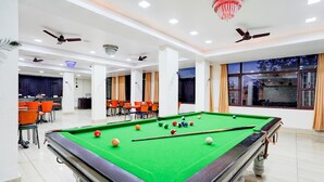 A pool table in a well-lit room with ceiling fans and a chandelier. - Townhouse Mall Road Near Library Chowk (Dehradun)