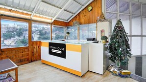 A cozy room with a wooden interior, a glass counter labeled "TOWNHOUSE," a small Christmas tree, and a view of the city through large windows. - Townhouse Mall Road Near Library Chowk (Dehradun)