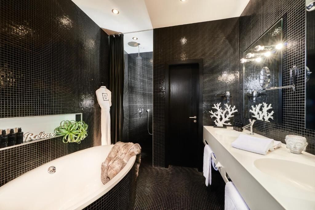 A modern bathroom with a bathtub, a large mirror, and a shower area.