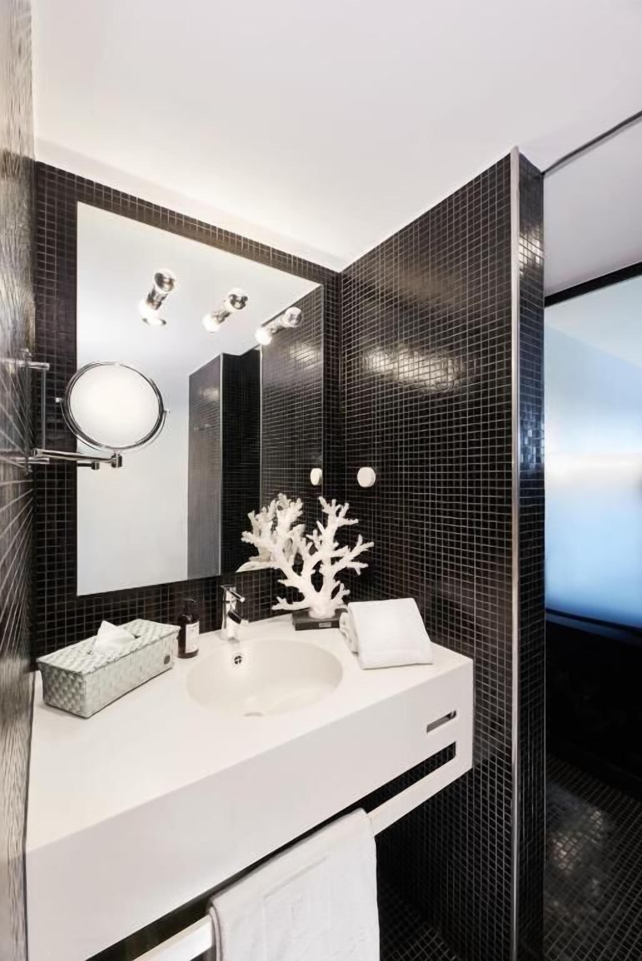 Un baño moderno con un espejo grande, un lavamanos blanco y un coral decorativo.