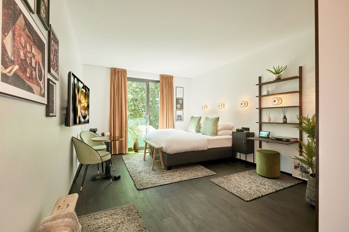 Un dormitorio moderno con cama, escritorio, silla y vistas al exterior.