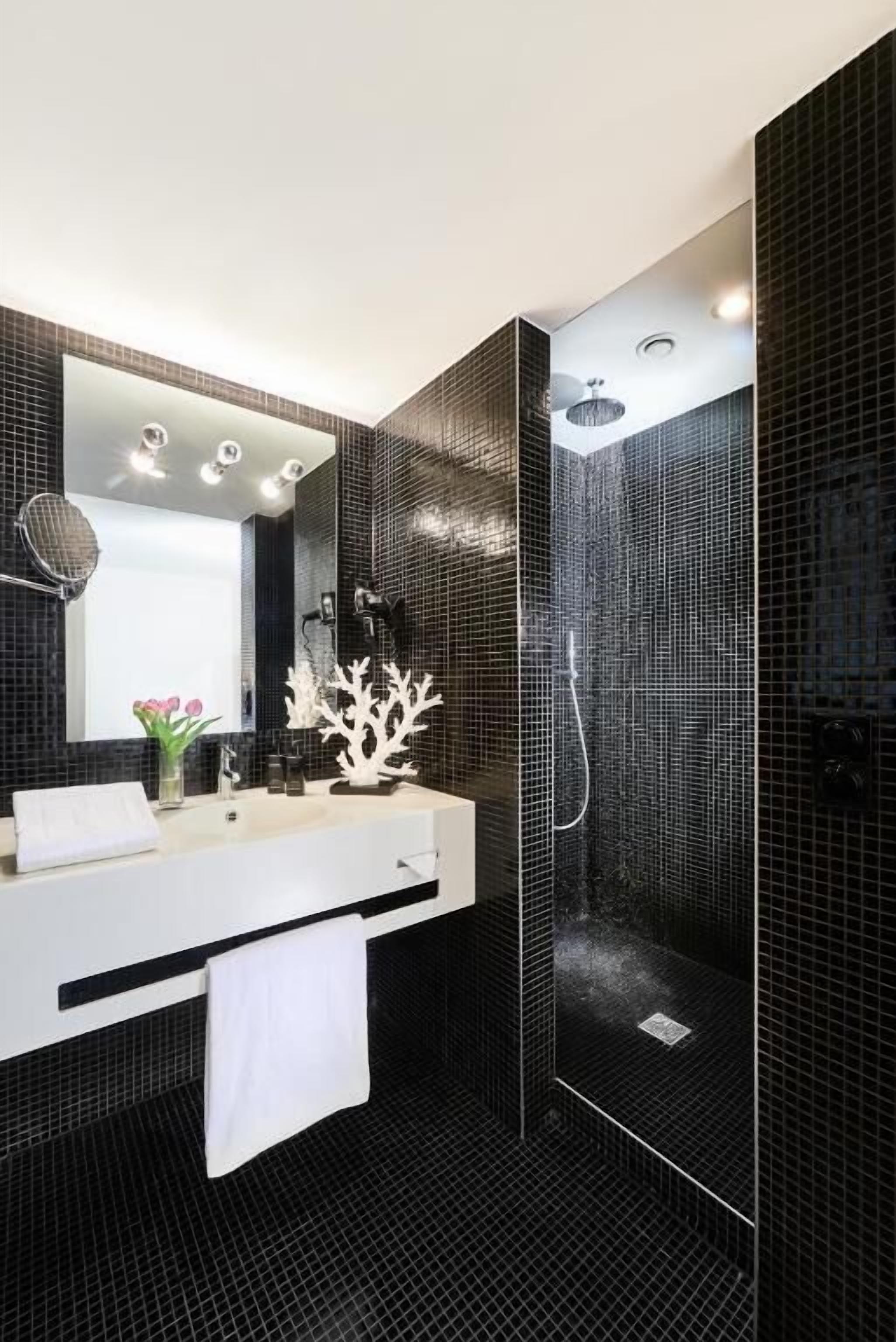 Un baño moderno con un espejo grande, un lavabo blanco y una cabina de ducha.