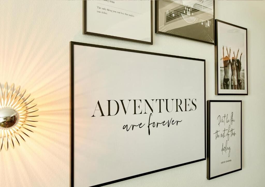 Un mur orné de citations et de photos encadrées, dont les suivantes : « Les AVENTURES sont éternelles » et « Ne soyez pas comme les autres et ne buvez pas. »