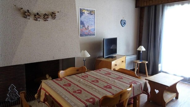 A cozy room with a dining table, chairs, a television, and a fireplace. - 200m from ski slopes, 1st floor, balcony, ski locker, 38m², Les Gets (Les Gets)