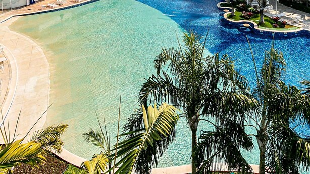 Un resort con una grande piscina, diversi balconi e vista sul mare.