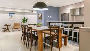 Una cucina moderna con zona pranzo, che include un tavolo di legno, sedie, una lampada a sospensione e un frigorifero.