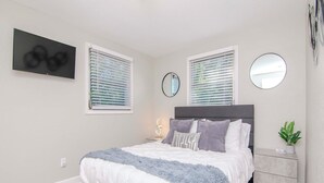 Quarto com cama, mesas de cabeceira, espelho e uma obra de arte na parede.