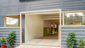 A modern building entrance with a clear pathway leading inside, potted plants on either side, and a visible door frame. - Deluxe Hebbal Townhouse (Bengaluru)