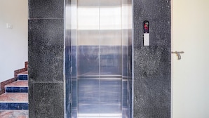 An elevator with a metallic interior, a control panel, and a door handle. - Deluxe Hebbal Townhouse (Bengaluru)